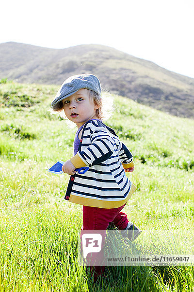 Porträt eines männlichen Kleinkindes  das beim Watscheln im Gras zurückblickt