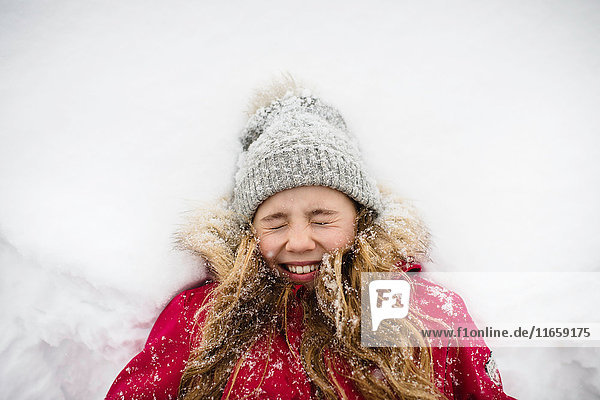 Girl lying on back in snow with eyes closed