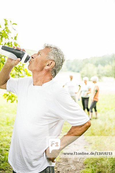 Älterer Mann trinkt Wasser aus einer Sportflasche.