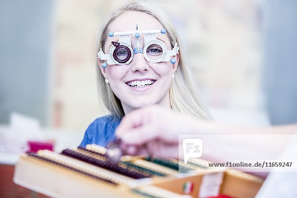 Porträt einer fröhlichen jungen Frau  die in einem Optikergeschäft eine Probefassung trägt  Nahaufnahme.