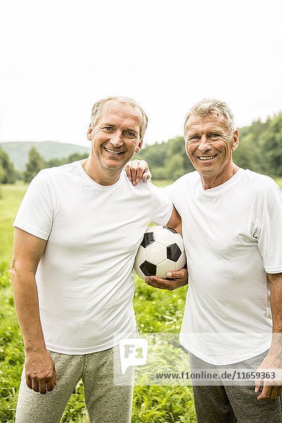 Zwei Männer  die die Arme umeinander legen und einen Fußball halten.