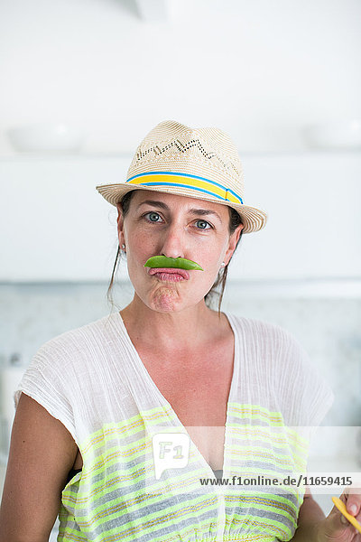 Bildnis einer mittelgroßen erwachsenen Frau mit Strohhut und Schnurrbart aus Erbsenschoten