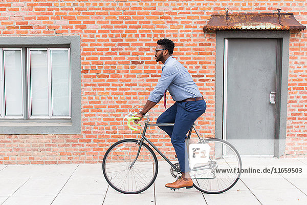 Seitenansicht eines jungen Mannes mit dem Fahrrad auf dem Bürgersteig