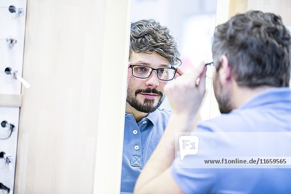 Mann beim Anprobieren einer Brille in einem Optikergeschäft.