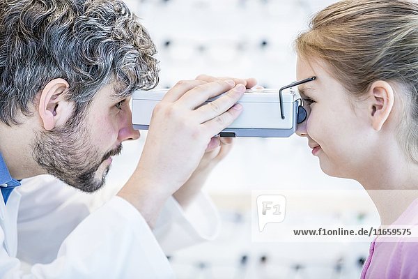 Optometrist performing eye test of young girl.