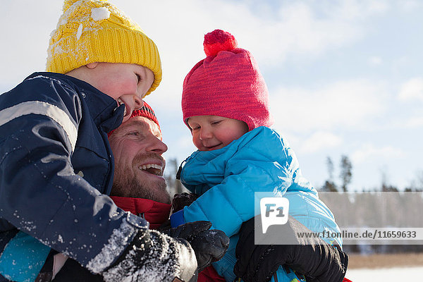 Father holding young sons  smiling  in winter setting