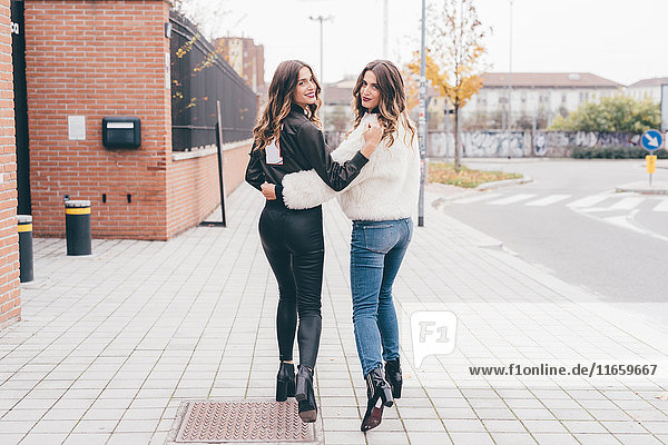 Porträt von Zwillingsschwestern  Spaziergang im Freien  Blick über die Schulter  Lächeln