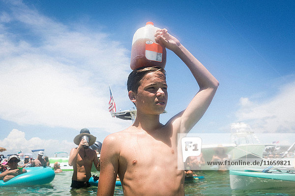 Teenager Junge im Wasser  der einen Saftkarton auf dem Kopf hält  Krebsinsel  Smaragdküste  Golf von Mexiko  USA