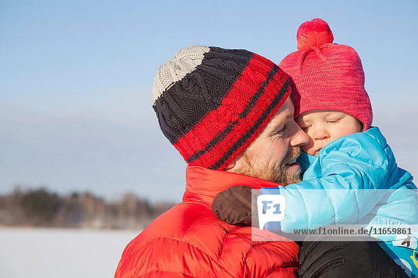 Father carrying young son in snow covered landscape