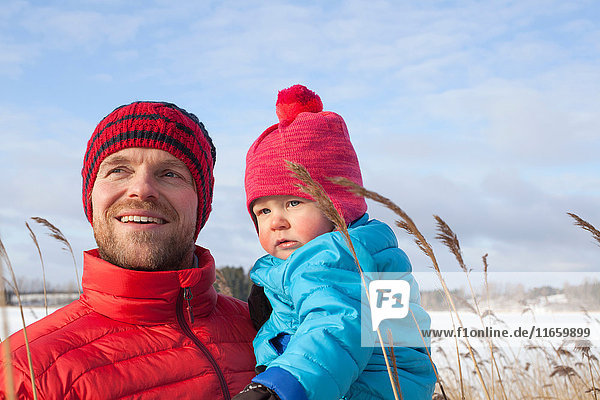 Father holding young son in snow covered landscape