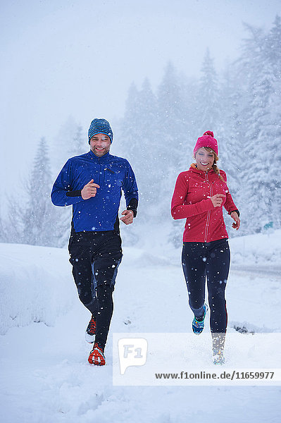 Female and male runners running in falling snow  Gstaad  Switzerland