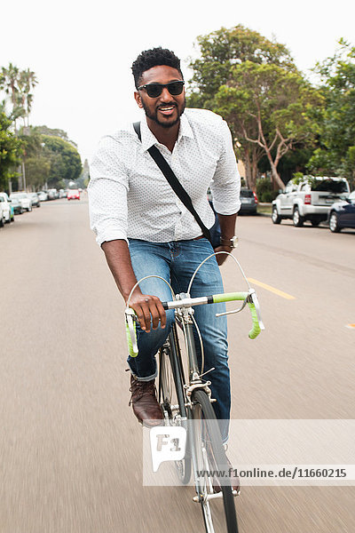 Happy young man cycling along road