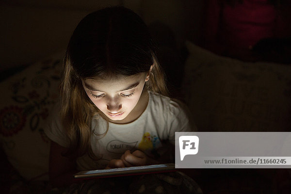 Mädchen in der Dunkelheit durch Licht vom digitalen Tablet beleuchtet