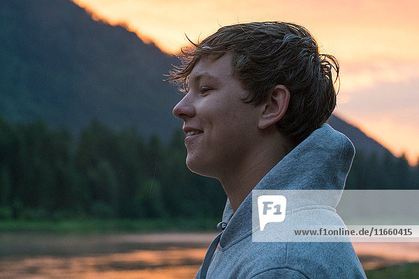 Portrait of teenage boy by river at sunset  Washington  USA