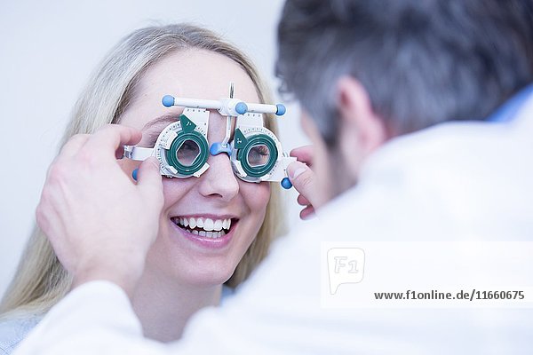 Ein Optiker führt einen Sehtest bei einer jungen Frau durch.
