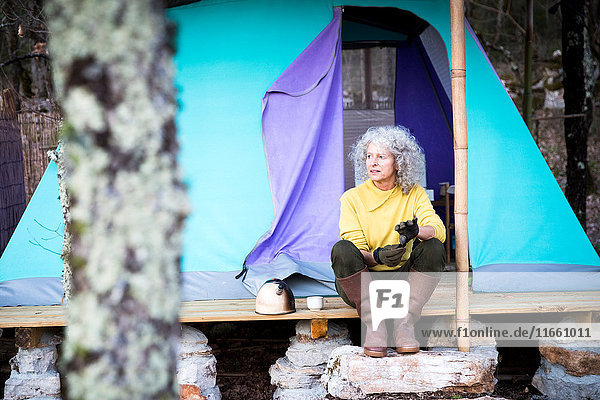 Reife Frau sitzt auf einer bewaldeten Camping-Veranda