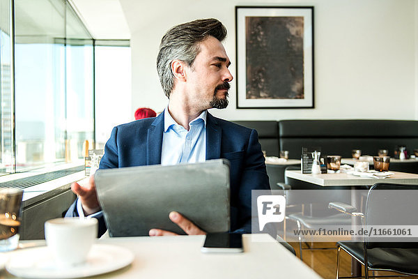 Geschäftsmann mit digitalem Tablett am Restaurantfenster  London  UK