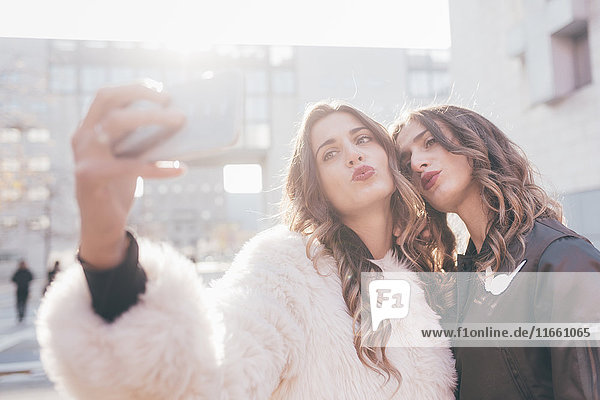 Zwillingsschwestern  draussen  Selfie  mit dem Smartphone