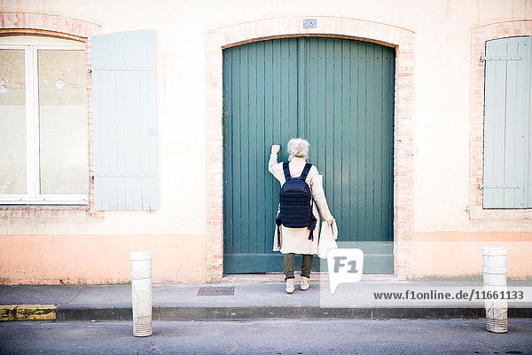 Rückansicht einer Frau  die an die Tür klopft  Bruniquel  Frankreich