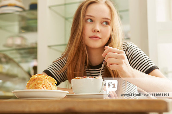 Girl in cafe stirring coffee