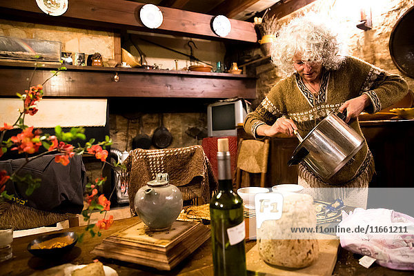 Reife Frau serviert Suppe in ihrer rustikalen französischen Küche