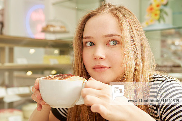 Mädchen in Café mit Kaffeetasse in der Hand