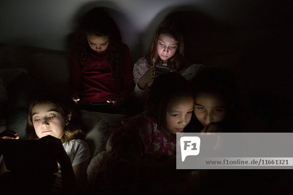 Mädchen in der Dunkelheit auf Pyjamaparty mit digitalem Tablet beleuchtet