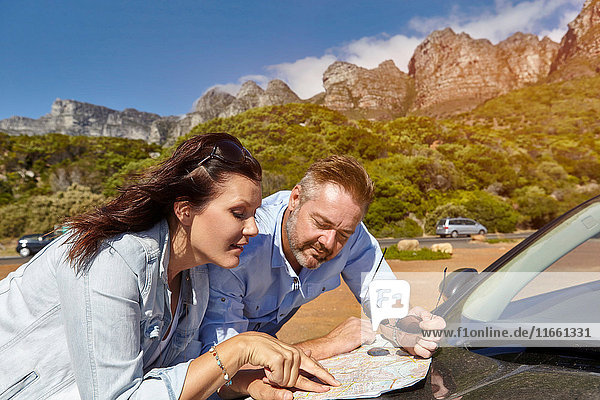 Paar lehnt auf der Motorhaube  schaut auf die Karte  Kapstadt