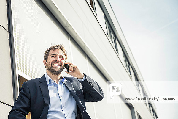 Businessman making smartphone call outside office building