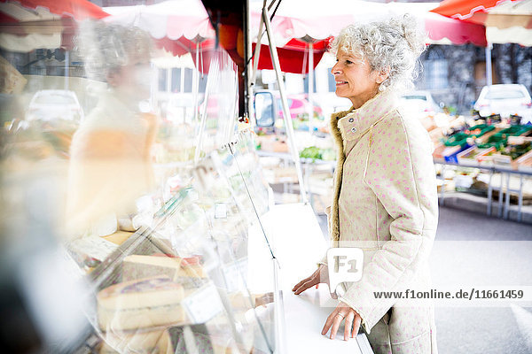 Mature female shopper buying cheese at local french market