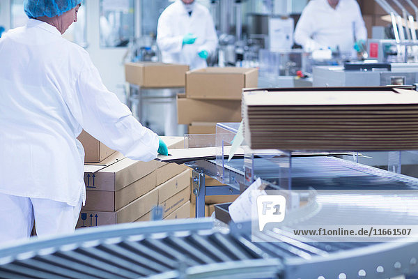 Arbeitnehmer,  die pharmazeutische Produkte an der Produktionslinie in einem pharmazeutischen Betrieb verpacken