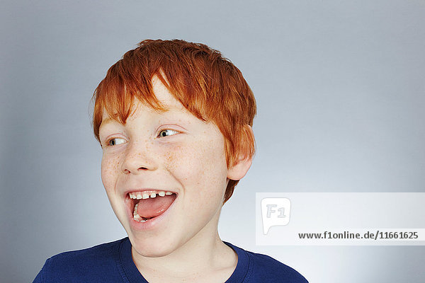 Studioporträt eines lächelnden rothaarigen Jungen mit seitlichem Blick
