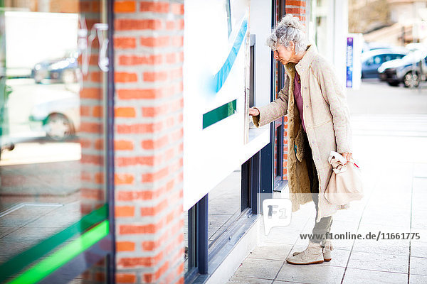 Reife Frau am lokalen französischen Geldautomaten