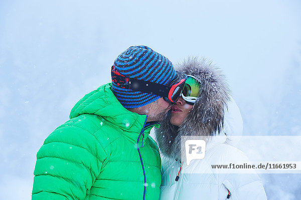 Mature couple kissing in falling snow  Gstaad  Switzerland