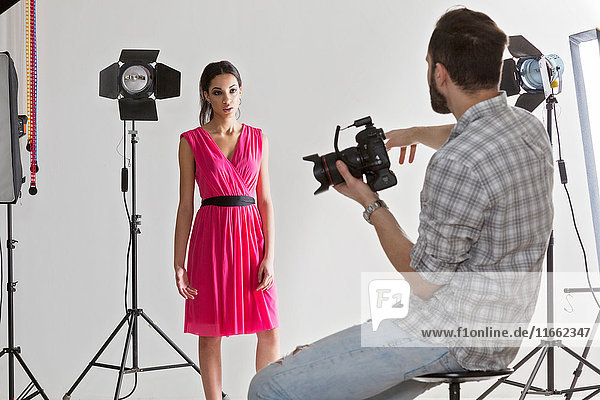 Photographer pointing at model in white backdrop photography studio shoot