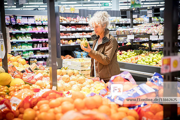 Reife Frau im Supermarkt  die sich frische Produkte ansieht