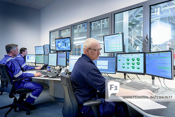 Workers in process control room in oil blending factory