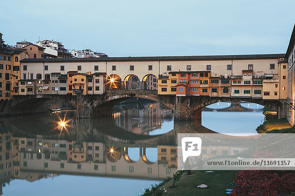 Der mittelalterliche Ponte Vecchio über den Arno im Zentrum der Stadt Florenz. Gebäude  die sich im Wasser spiegeln.
