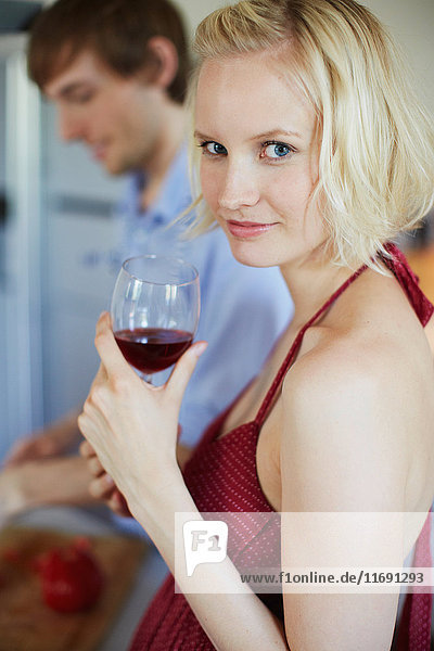 Smiling woman drinking wine in kitchen