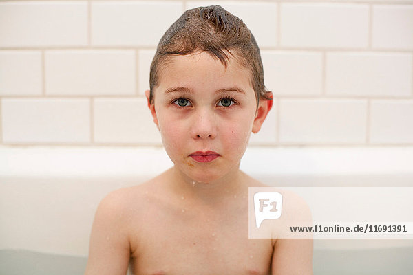 Junge mit traurigem Gesicht in Badewanne getaucht