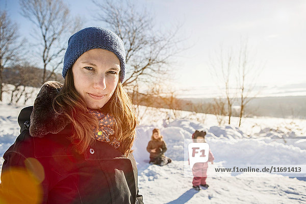 Frau geht mit Kindern im Schnee spazieren