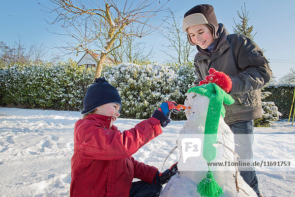Jungen machen Schneemann im Garten