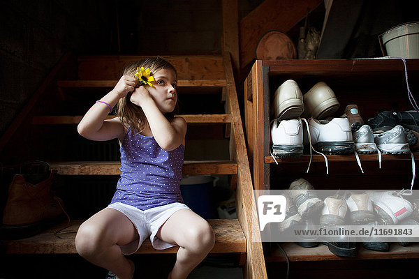 Kleines Mädchen auf Kellertreppe  eine Blume im Haar