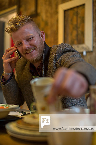 Mann telefoniert bei Tisch mit Handy