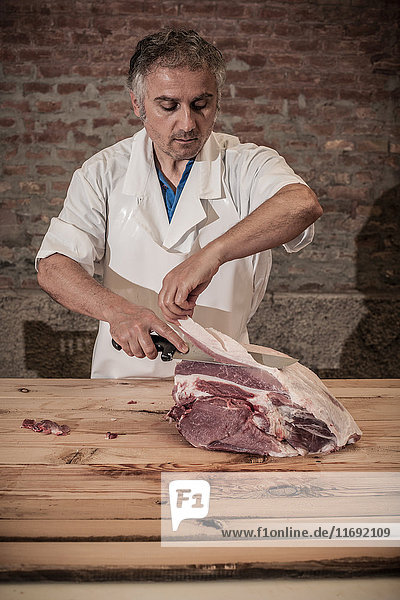 Butcher carving meat in shop