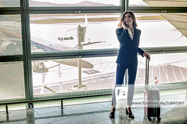 Junge Frau am Handy im Flughafen
