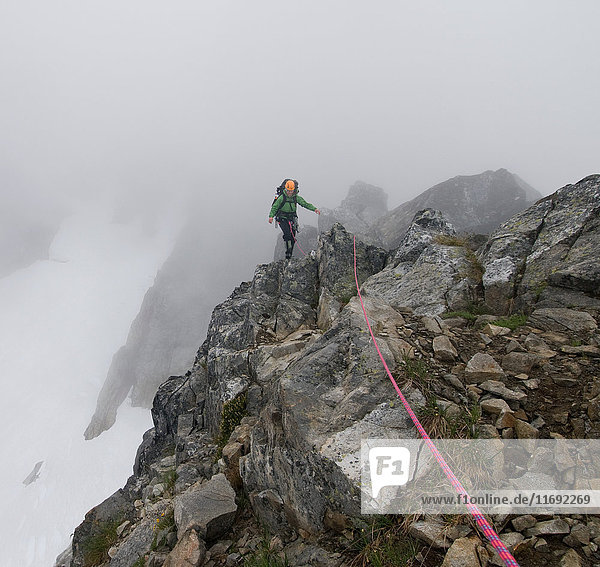 Weibliche Bergsteigerin überquert Felsgrat  Picket Pass  North Cascades National Park  WA  USA