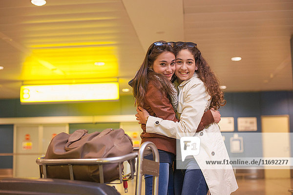 Two teenage girls hugging in airport
