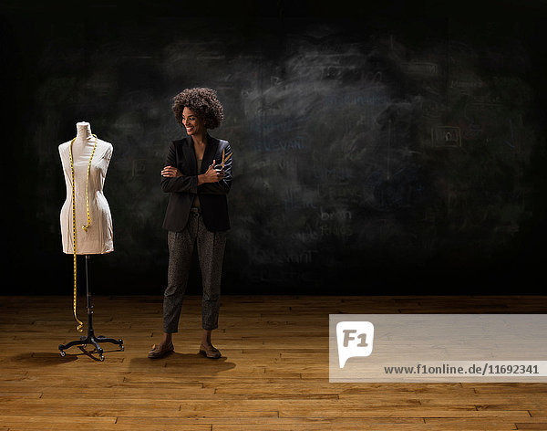 Businesswoman by blackboard with tailors dummy