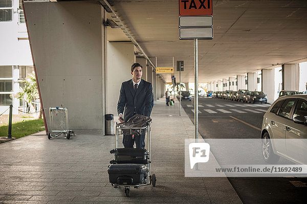 Junger Mann mit Gepäckwagen im Flughafen